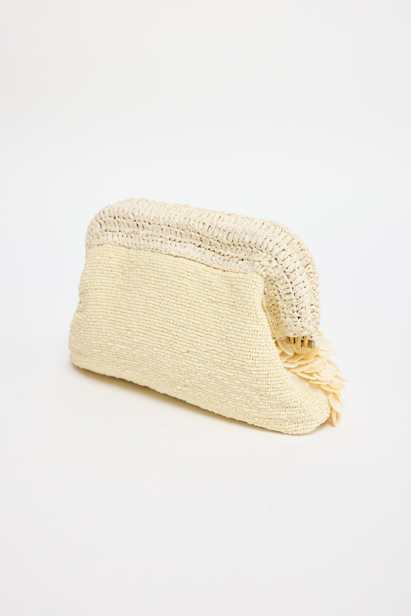 Sandy Clutch in creme - three-quarter angle showing the dimensional shell fringe and gold-tone frame clasp