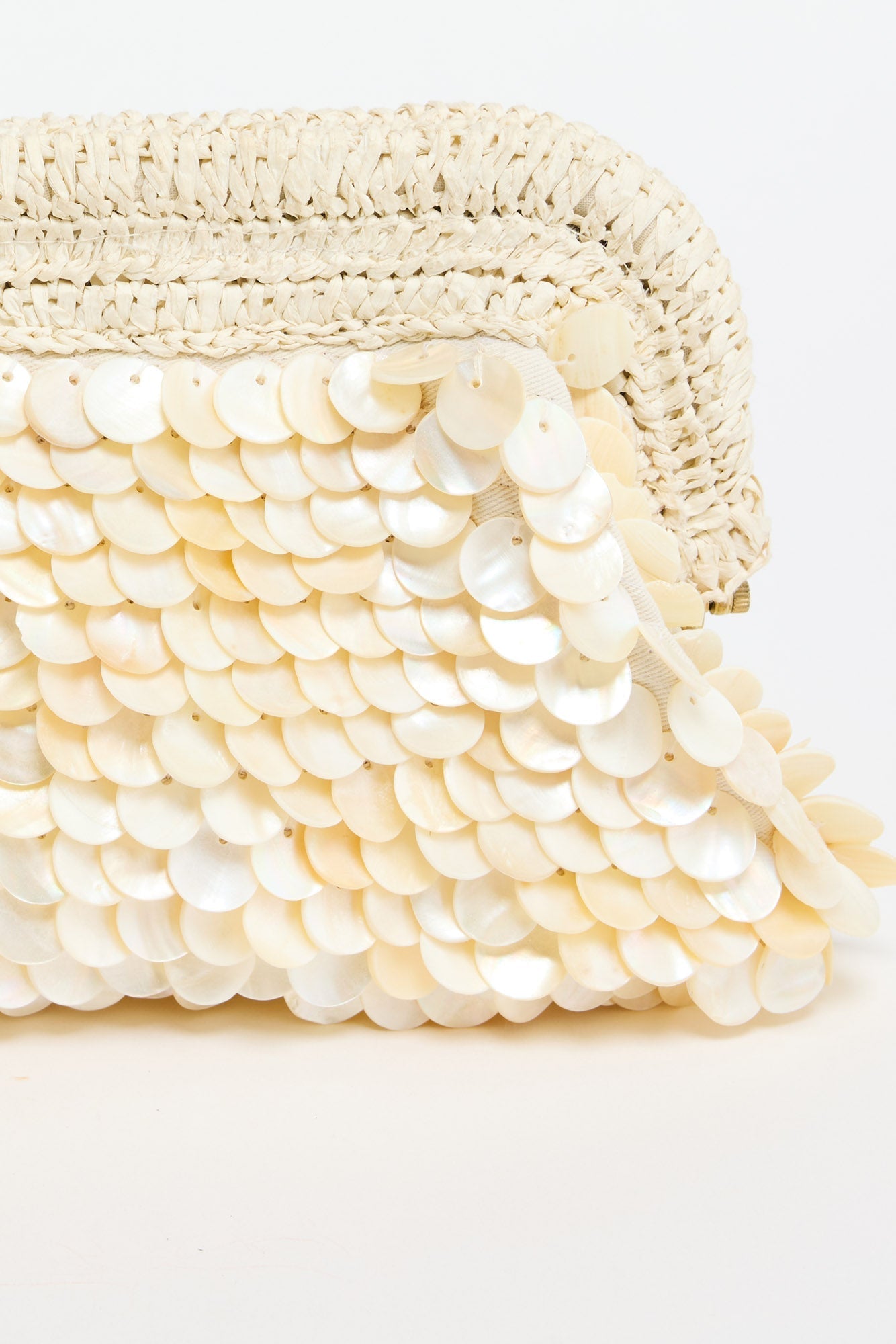 Sandy Clutch in creme - close-up of the woven raffia trim and gold-tone frame hardware at the corner