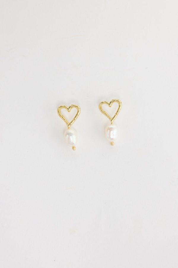 Pair of gold-tone open heart stud earrings with a single freshwater pearl drop and a small gold bead below, laid flat on a white background