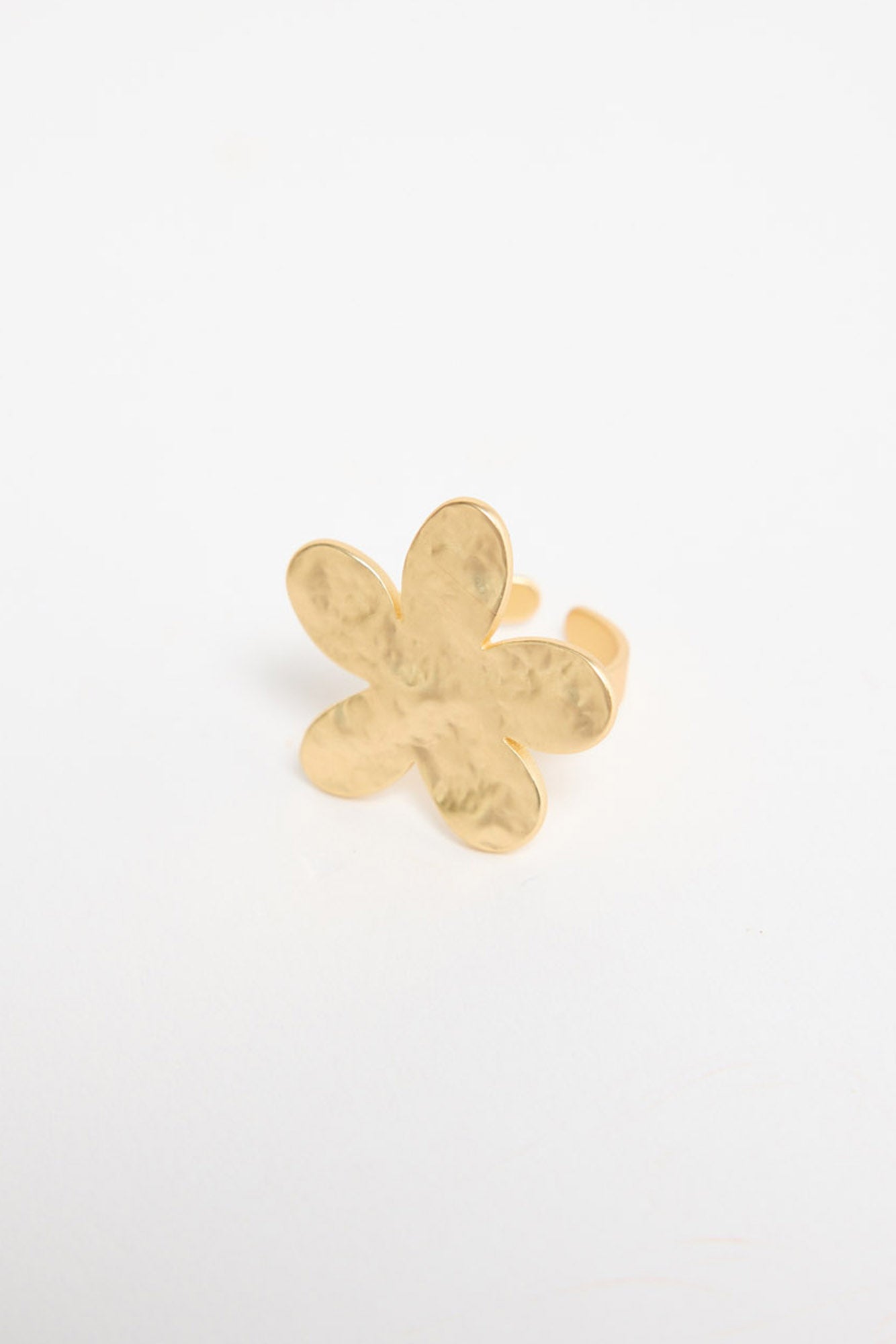 Gold-tone adjustable ring with a large daisy flower top featuring textured petals and a crystal centre, shown at an angle on a white background