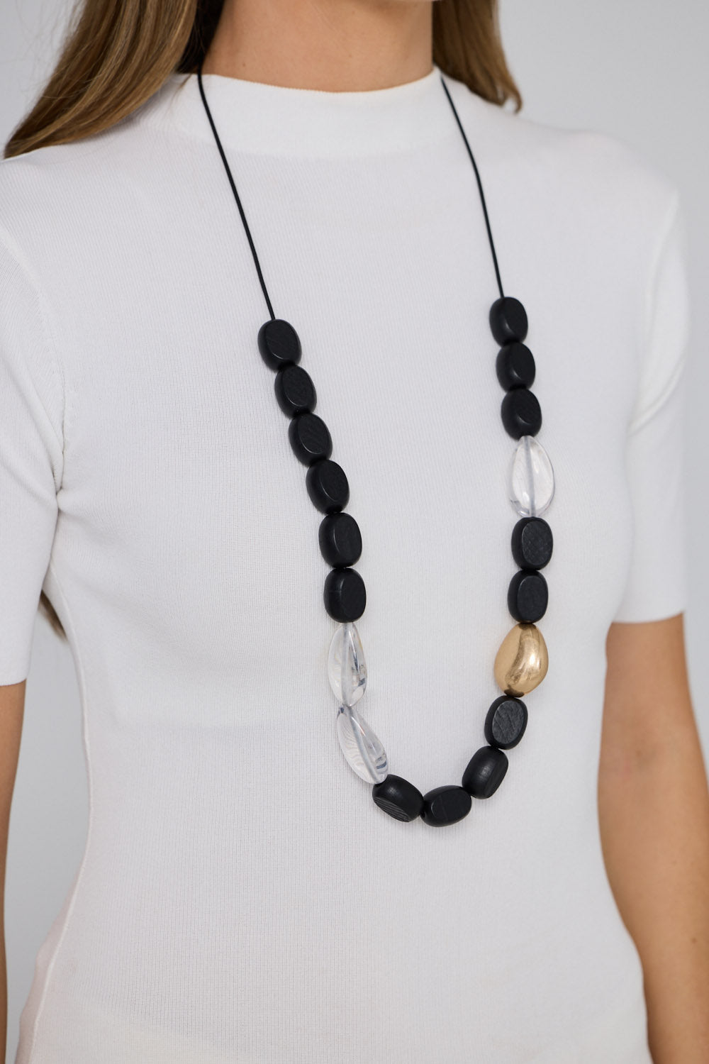 Chester Necklace in black and gold, with mixed material detailing and metal accents, styled view.