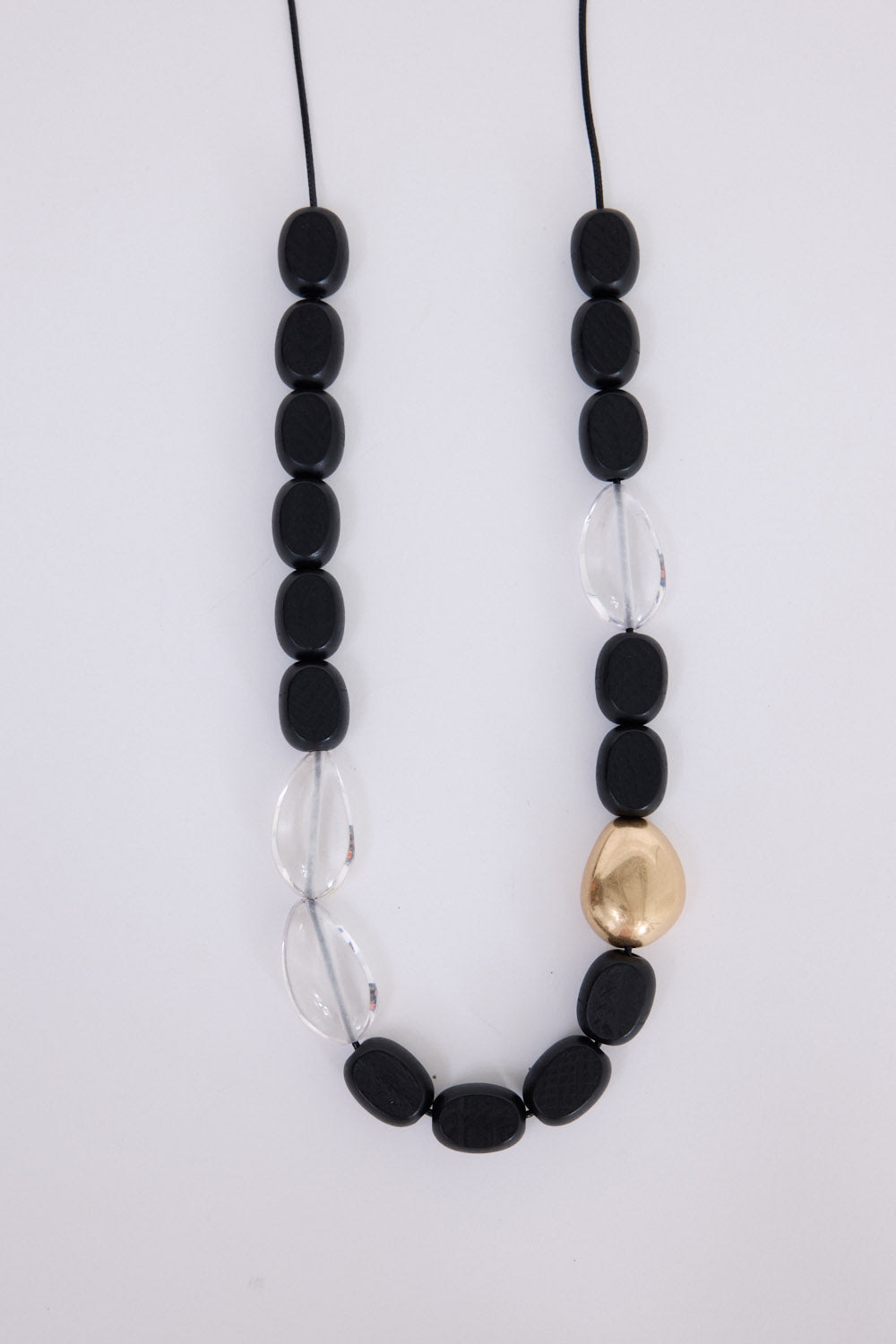 Chester Necklace in black and gold, with mixed material detailing and metal accents, angled view.