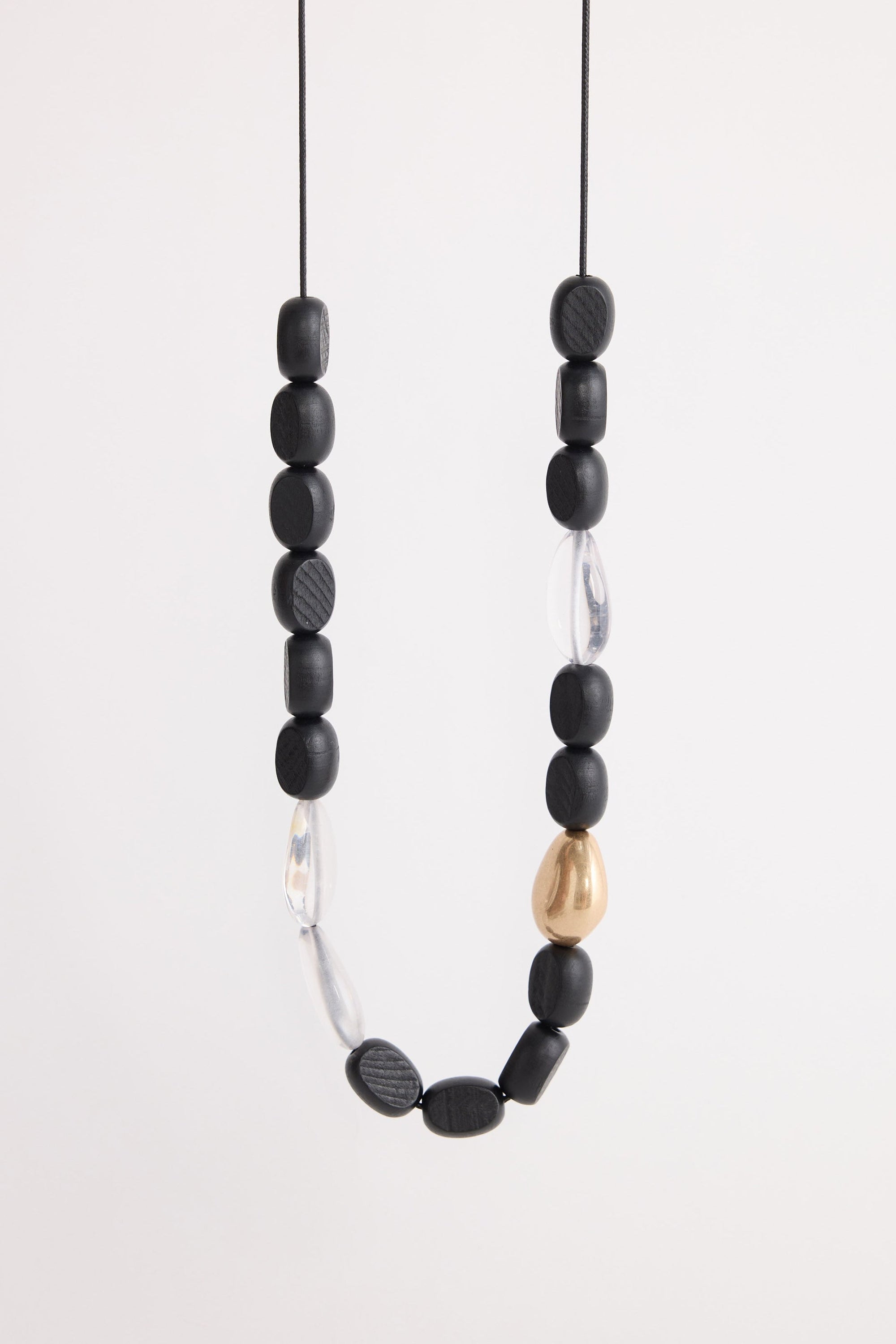Chester Necklace in black and gold, with mixed material detailing and metal accents, side view.
