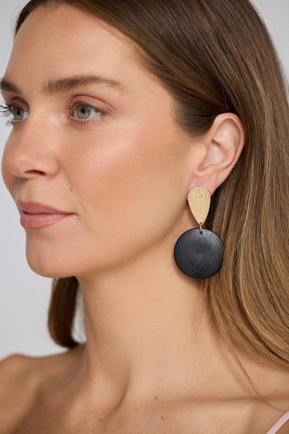 Model wearing Parker Earrings in black and gold, with textured top detail, side profile view.