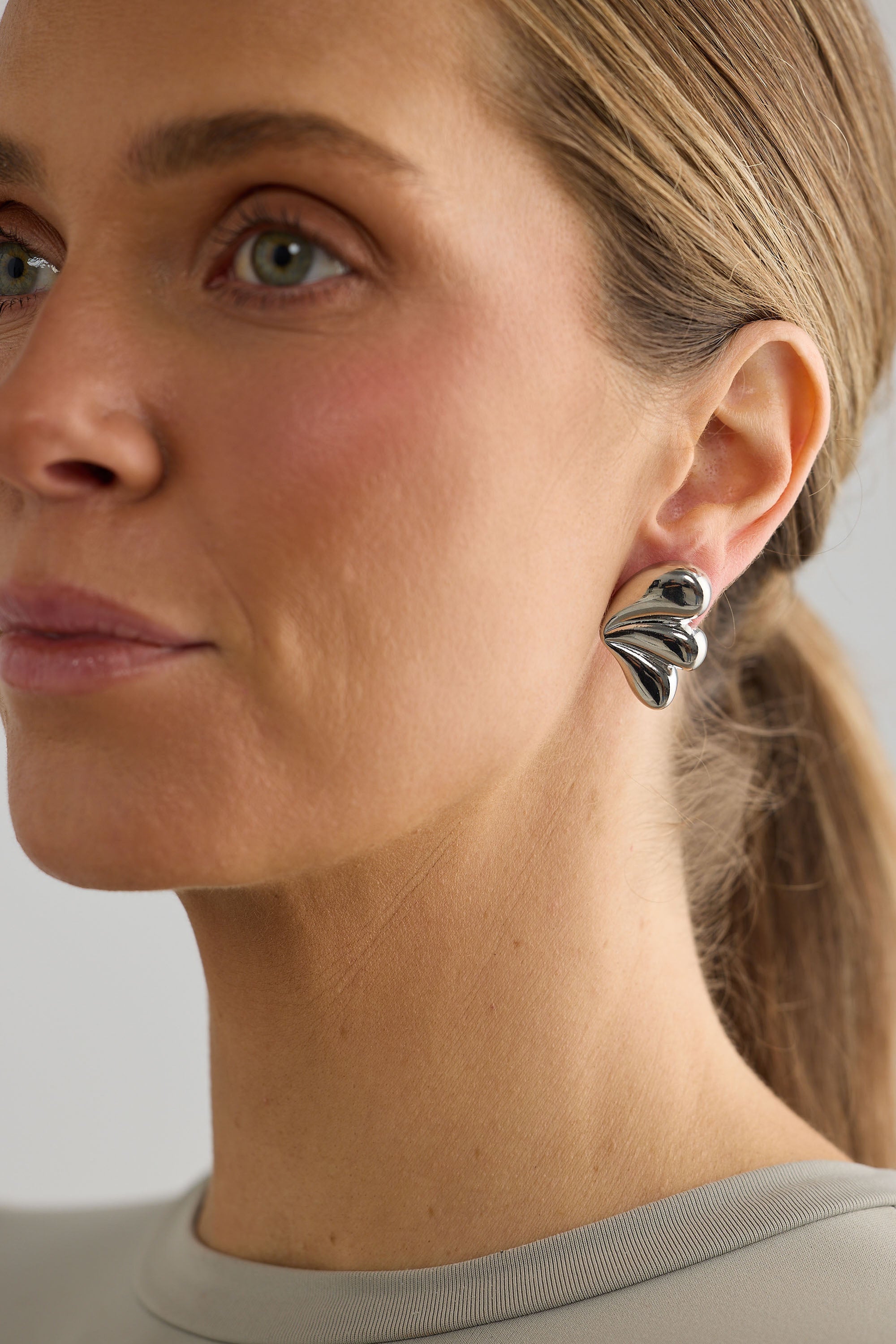 Close-up of a woman wearing silver butterfly earrings with a neutral background
