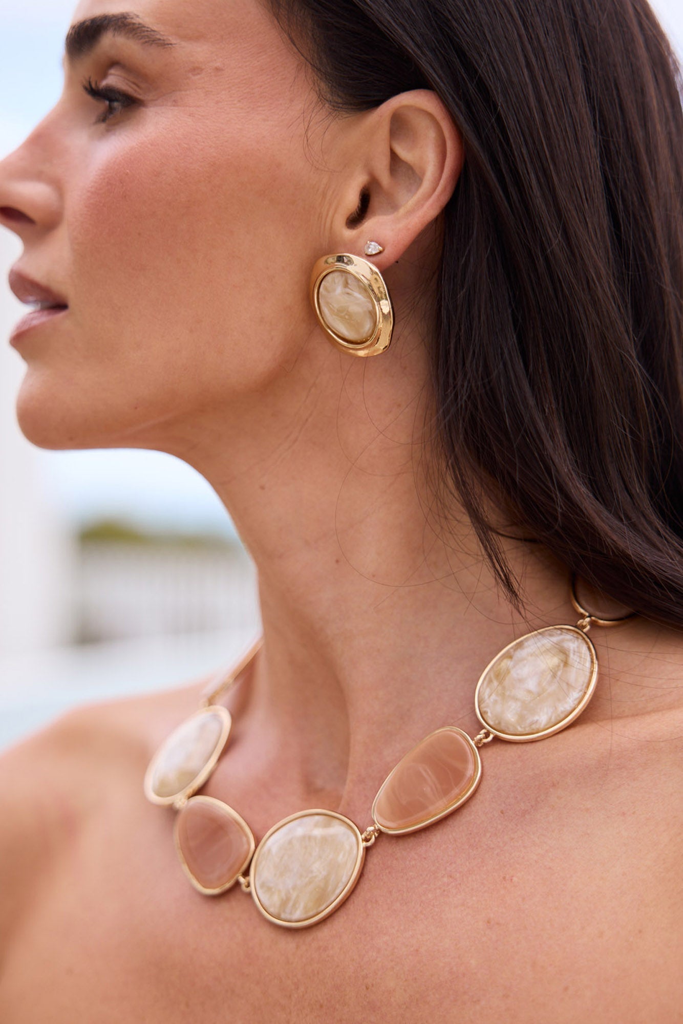 Campaign close-up of model wearing Ariel Necklace in salmon with white, showing the necklace against the collarbone
