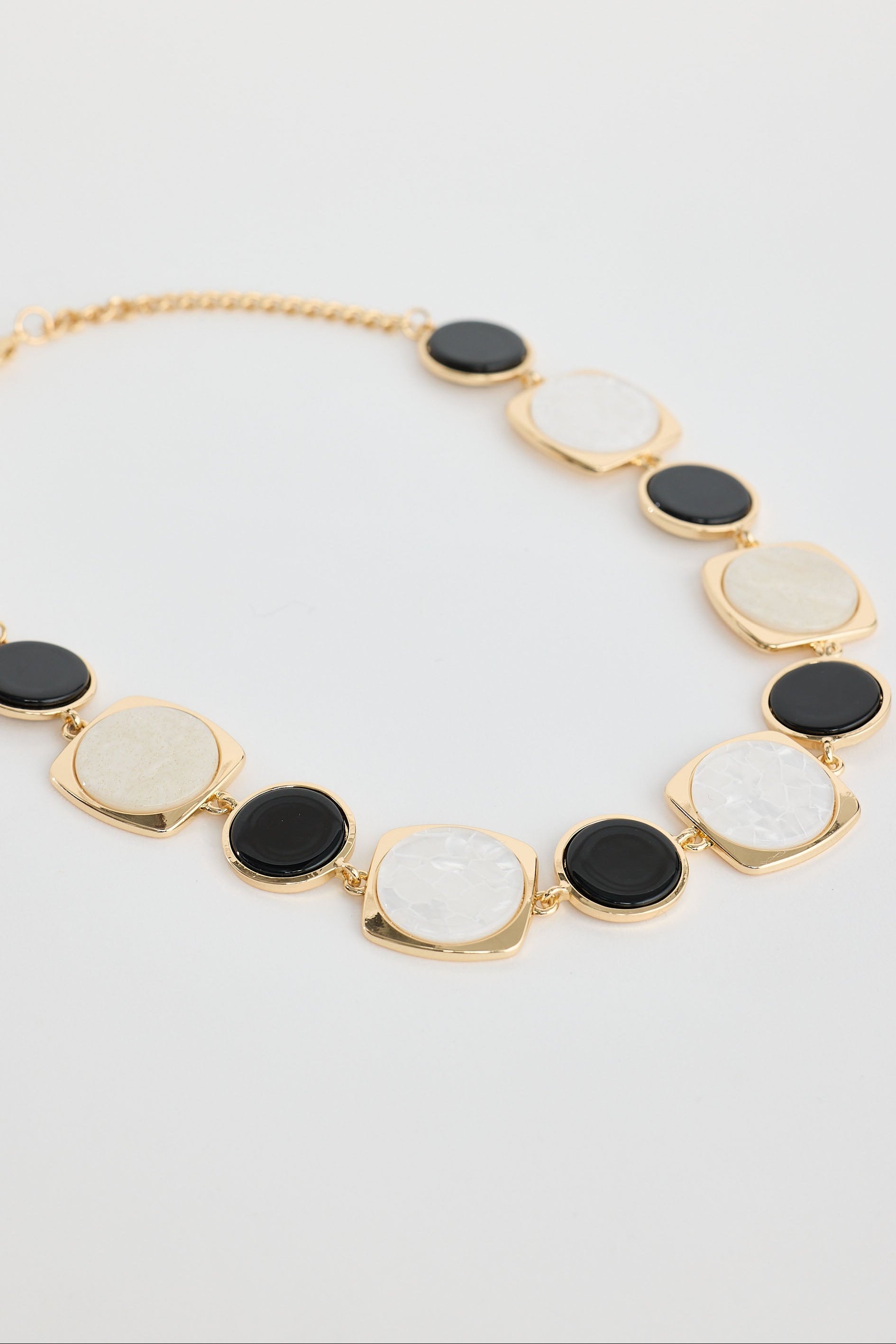 Necklace with black and white circular pendants on a plain background