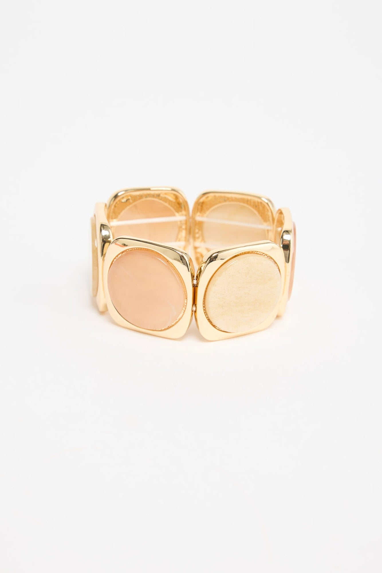 Gold-tone stretch bracelet with alternating square panels set with salmon-pink and cream resin discs, shown flat on a white background