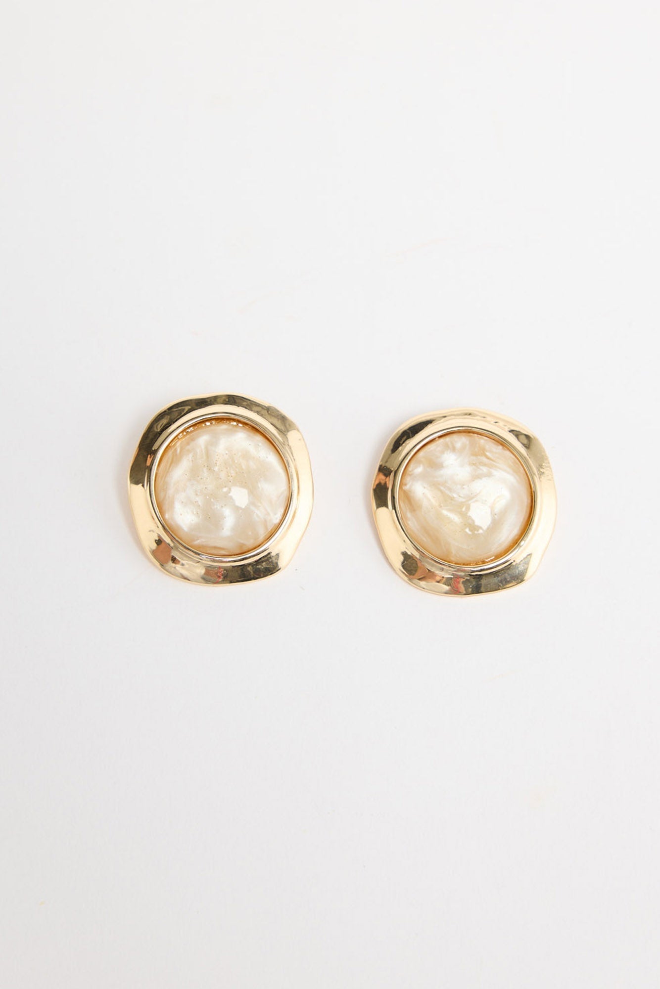 Pair of large square gold-tone stud earrings each set with a round cream mother-of-pearl resin stone in a hammered bezel, laid flat on a white background
