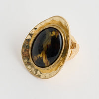 Gold ring with a black gemstone on a light gray background
