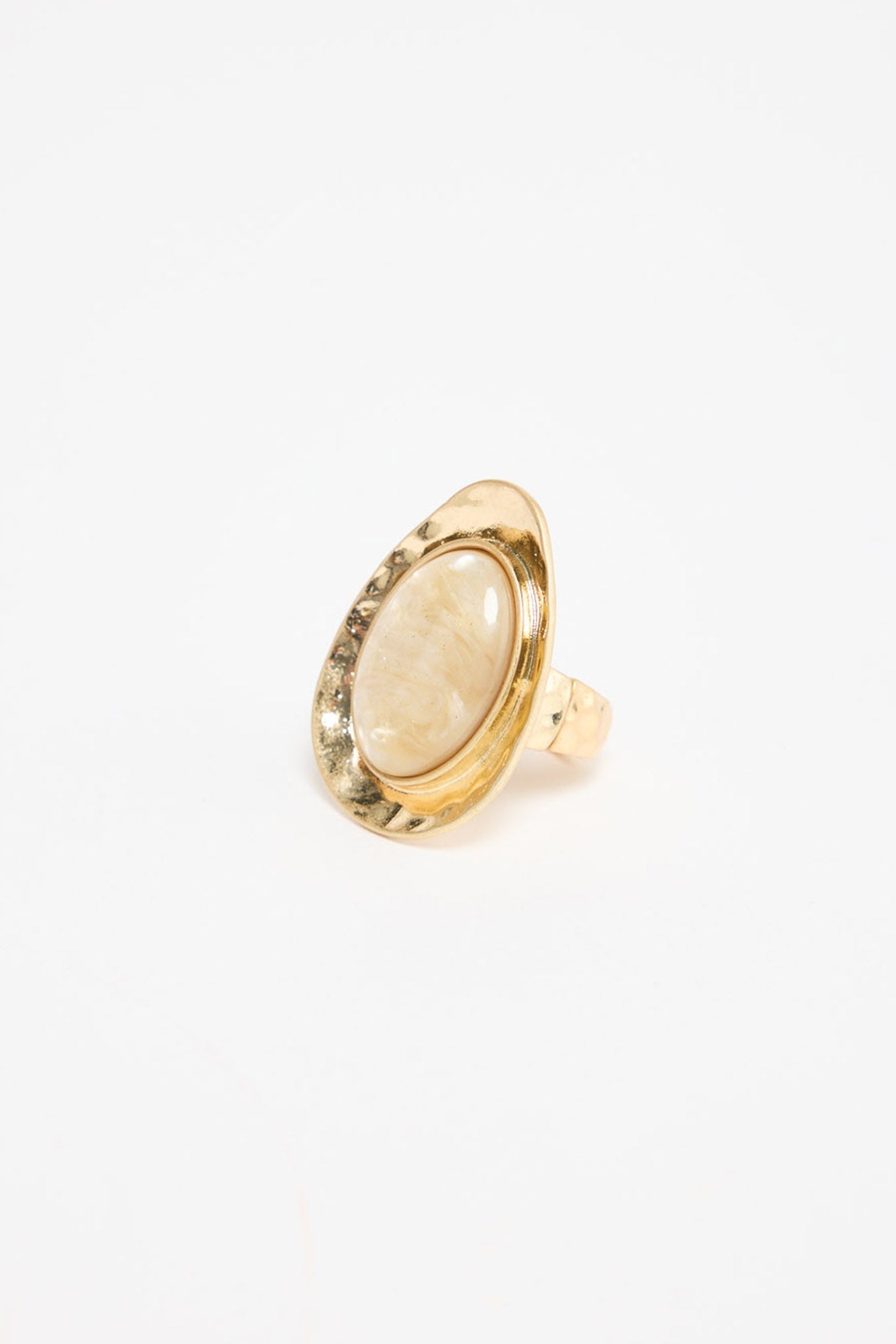 Large oval gold-tone adjustable statement ring with a cream mother-of-pearl resin stone set in a wide hammered bezel, shown at an angle on a white background
