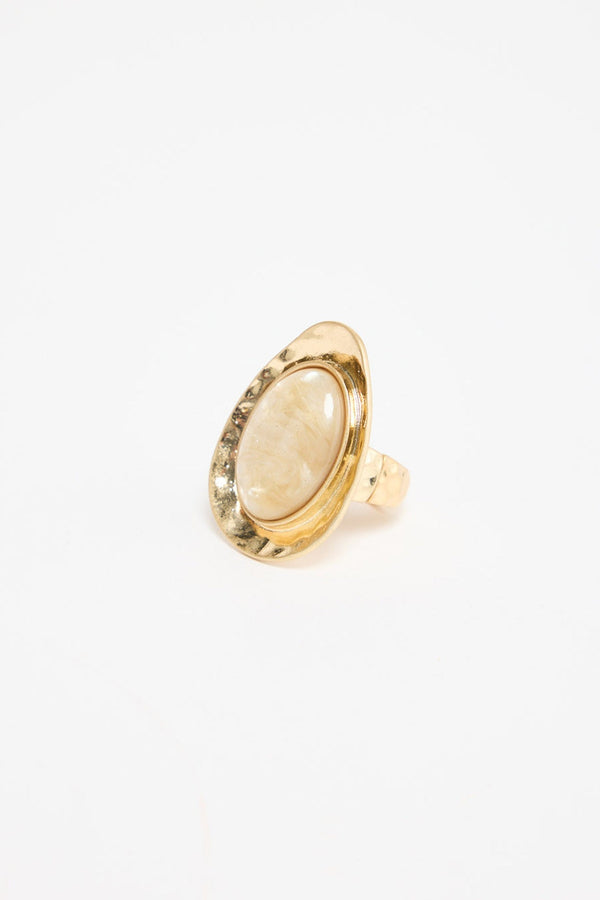 Large oval gold-tone adjustable statement ring with a cream mother-of-pearl resin stone set in a wide hammered bezel, shown at an angle on a white background