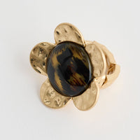Gold earring with a dark gemstone on a white background