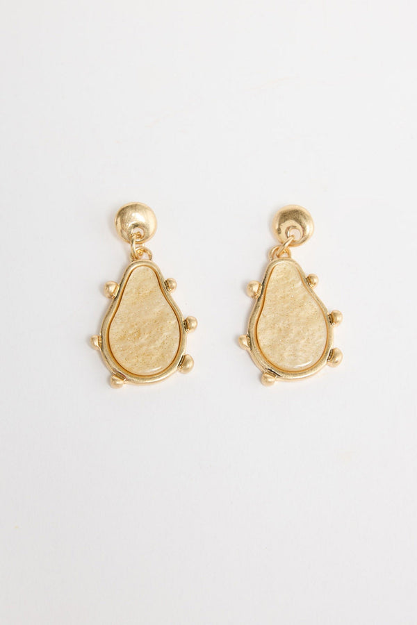 Pair of gold-tone drop earrings with a round ball stud and a teardrop-shaped cream resin pendant framed in gold with small ball accents, laid flat on a white background
