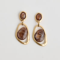 Gold earrings with brown stones on a light gray background