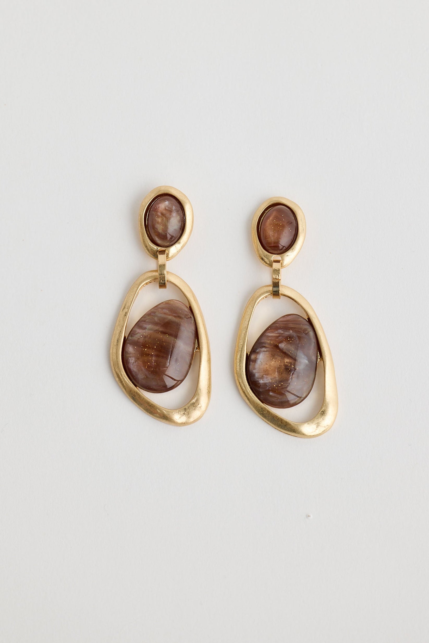 Gold earrings with brown stones on a light gray background
