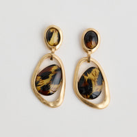 Pair of gold earrings with tiger eye stones on a light gray background