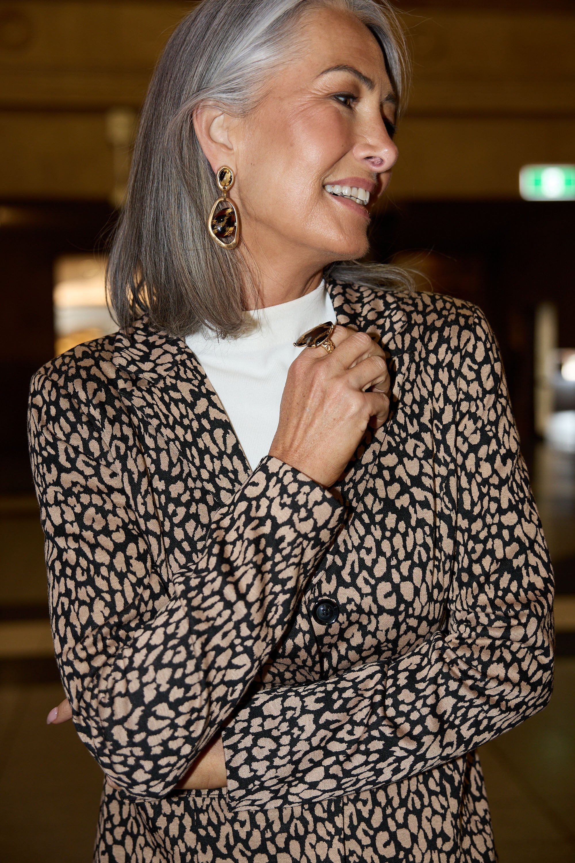 Woman wearing a leopard print jacket with a blurred indoor background