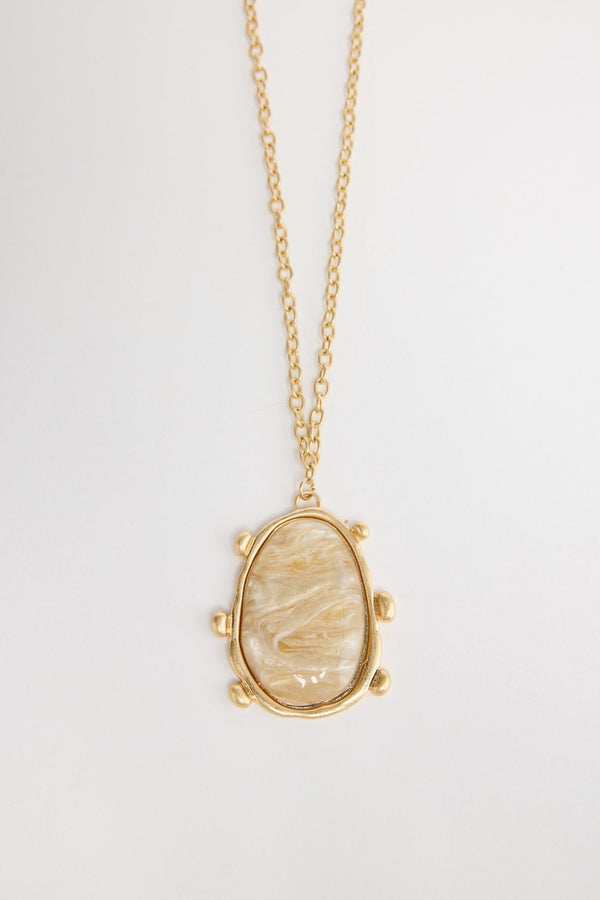 Gold-tone chain necklace with a large oval cream mother-of-pearl resin pendant set in a wide hammered bezel with small ball accents, shown flat on a white background