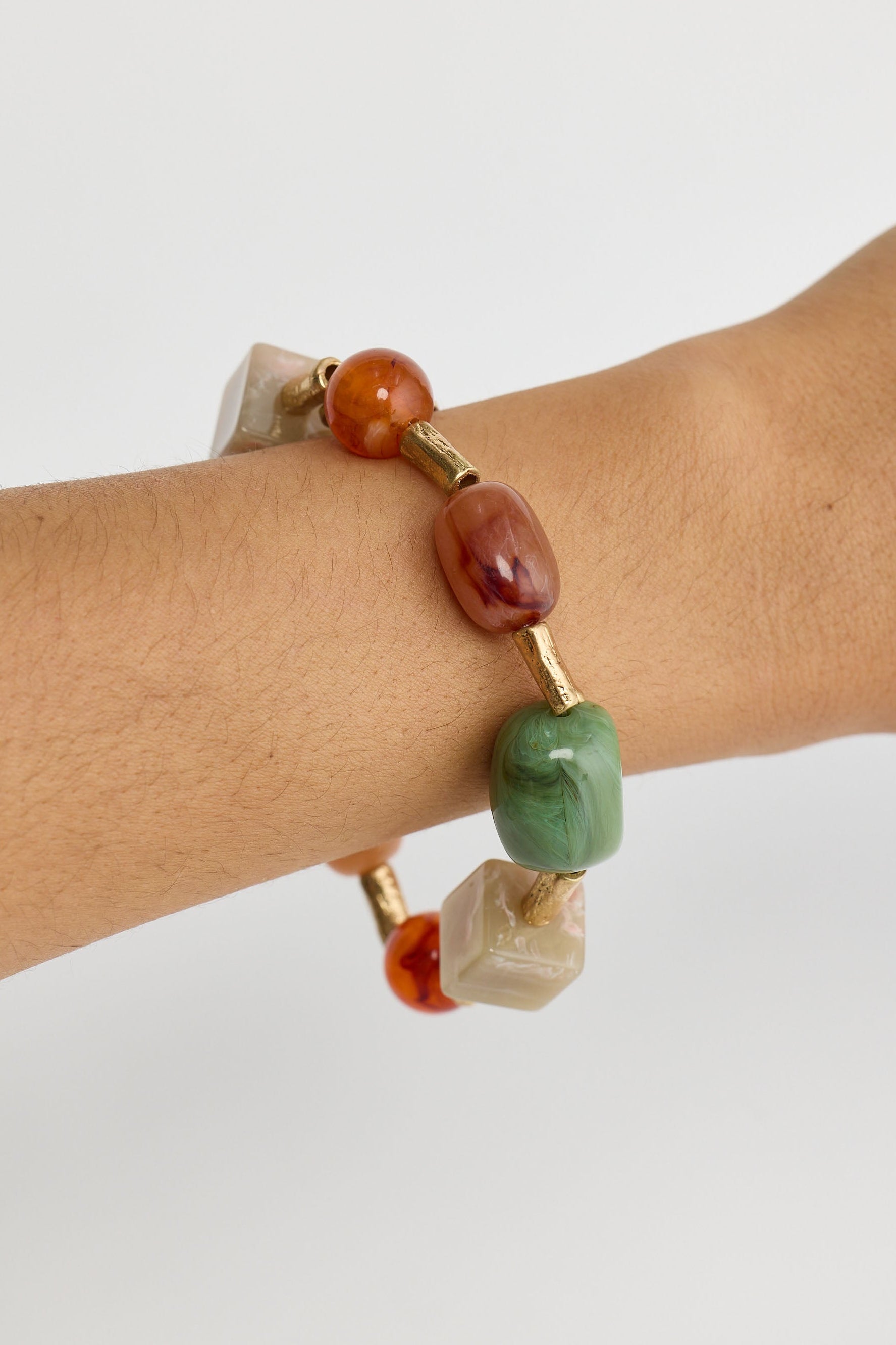 Bracelet with multicolored beads on a wrist against a white background