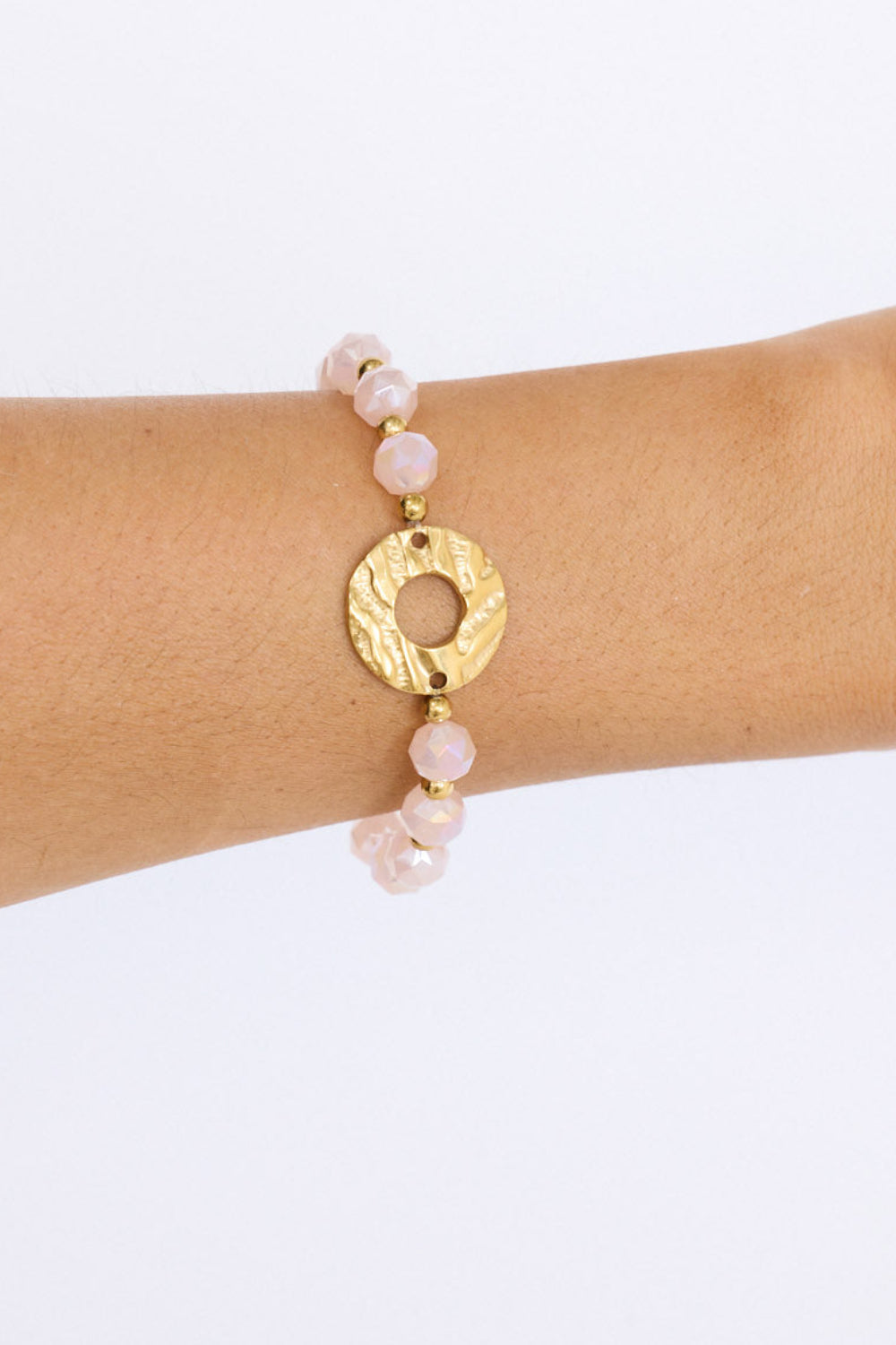 Model wearing Clarke Bracelet in pink with statement gold charm detail, angled on-wrist view.