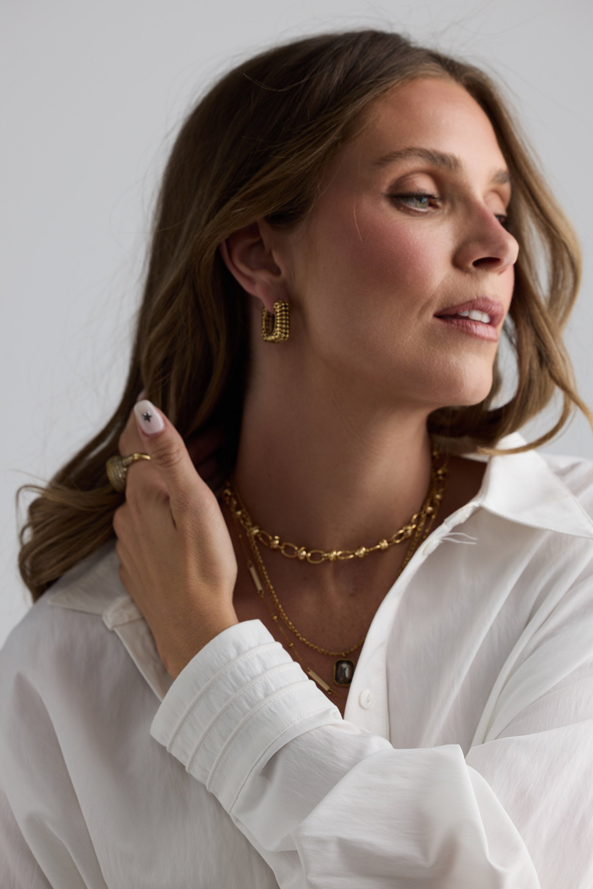 Model wearing Uma Necklace in gold with a fine textured link design, styled view.