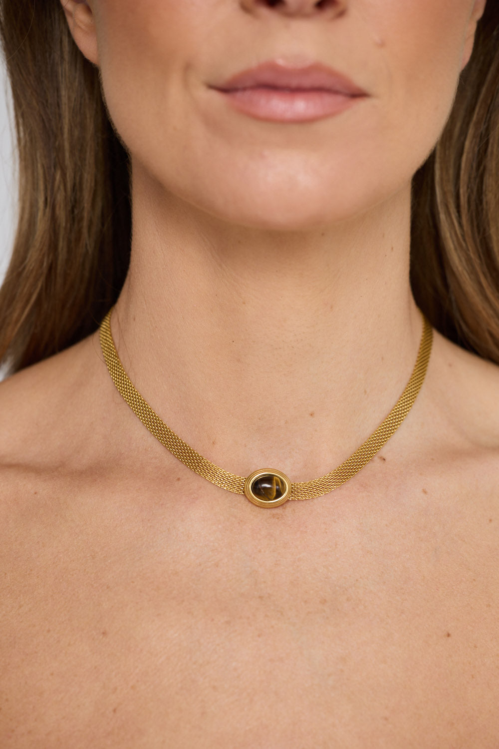 Dorris Necklace in amber with a central oval stone detail, front view.