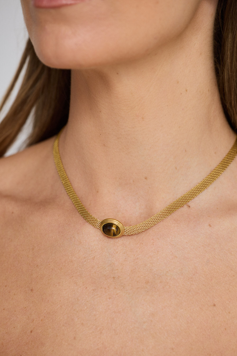 Dorris Necklace in amber with a central oval stone detail, neckline styled view.