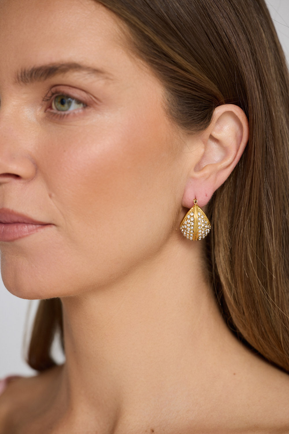 Model wearing Elvana Earrings in gold with layered pave crystal detailing, close-up view.