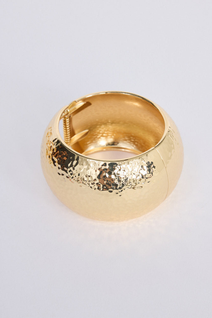 Model wearing Maura Bangle in gold with snap lock closure and hinge for easy wear, on-wrist view.