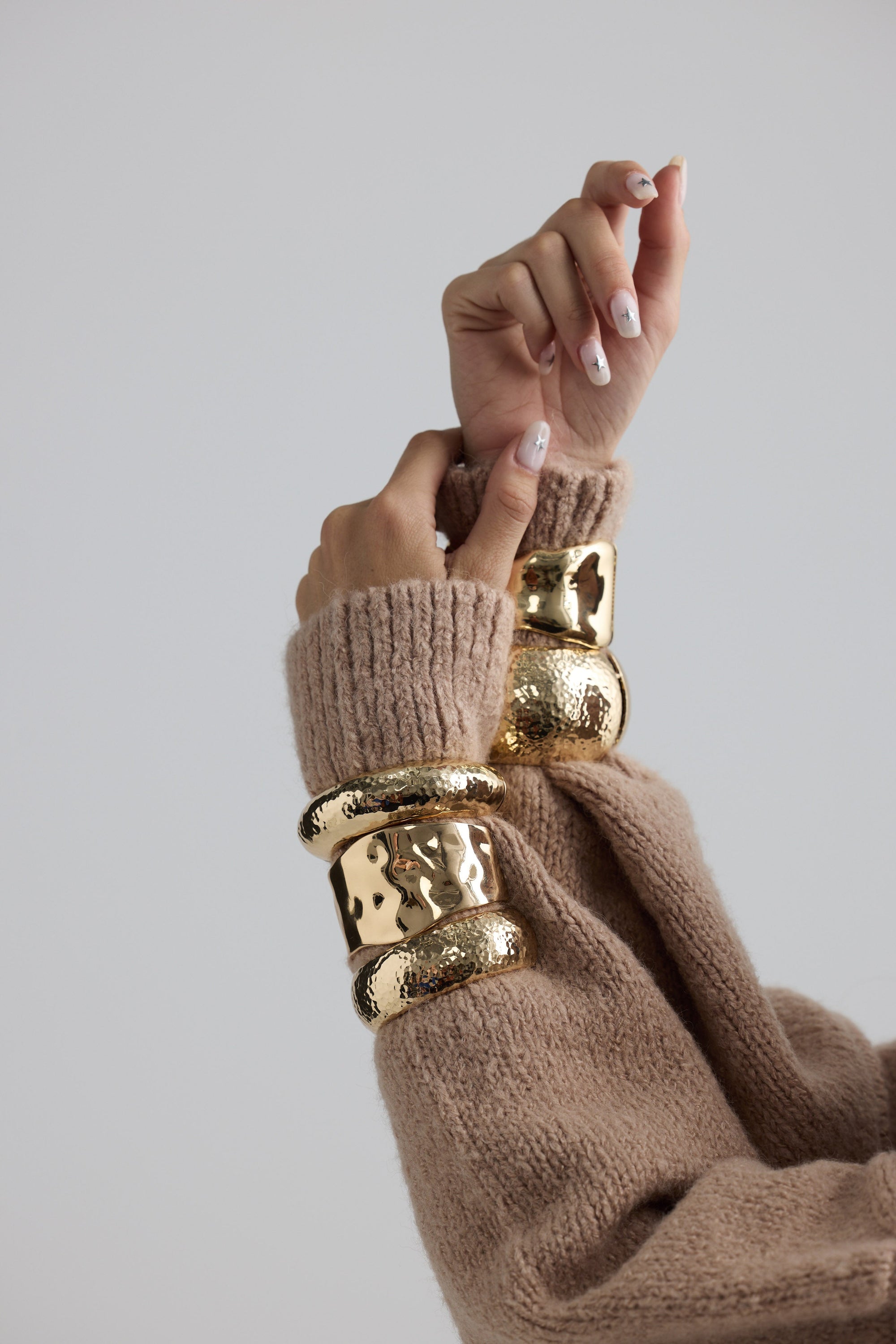 Model wearing Maura Bangle in gold with snap lock closure and hinge for easy wear, on-wrist view.