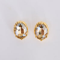 Unice Earrings in clear with a faceted stone set in a textured gold surround, front view.