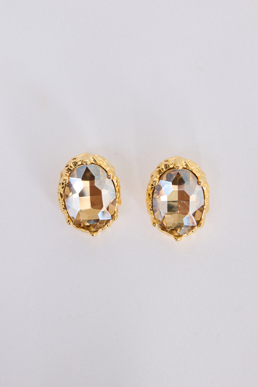 Unice Earrings in clear with a faceted stone set in a textured gold surround, front view.