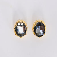 Gold-framed earrings with smoky gemstones on a light gray background