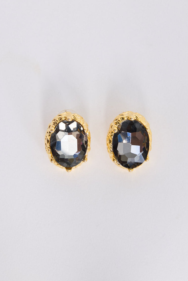 Gold-framed earrings with smoky gemstones on a light gray background