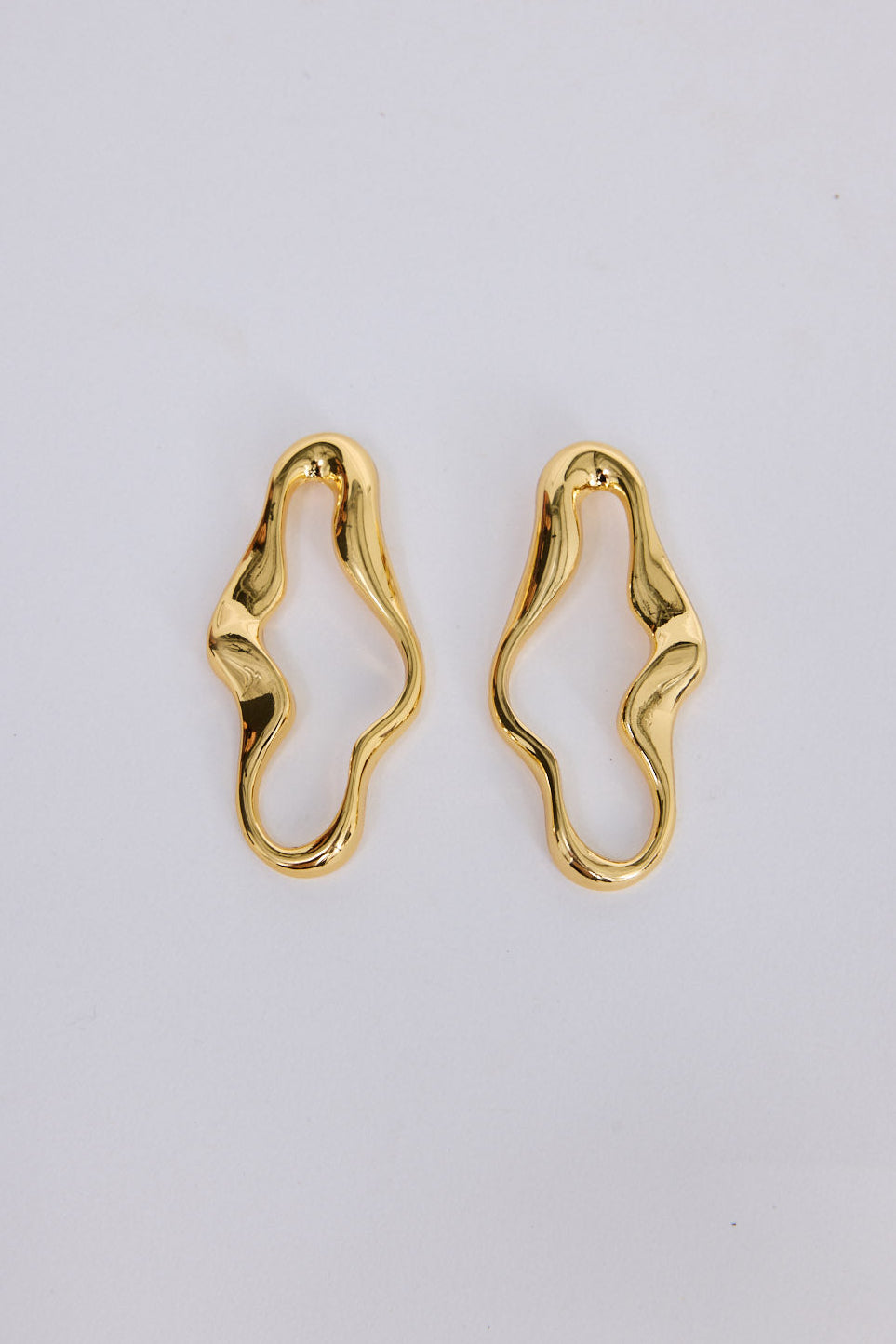Benny Earrings in gold with a fluid sculptural silhouette, front view.