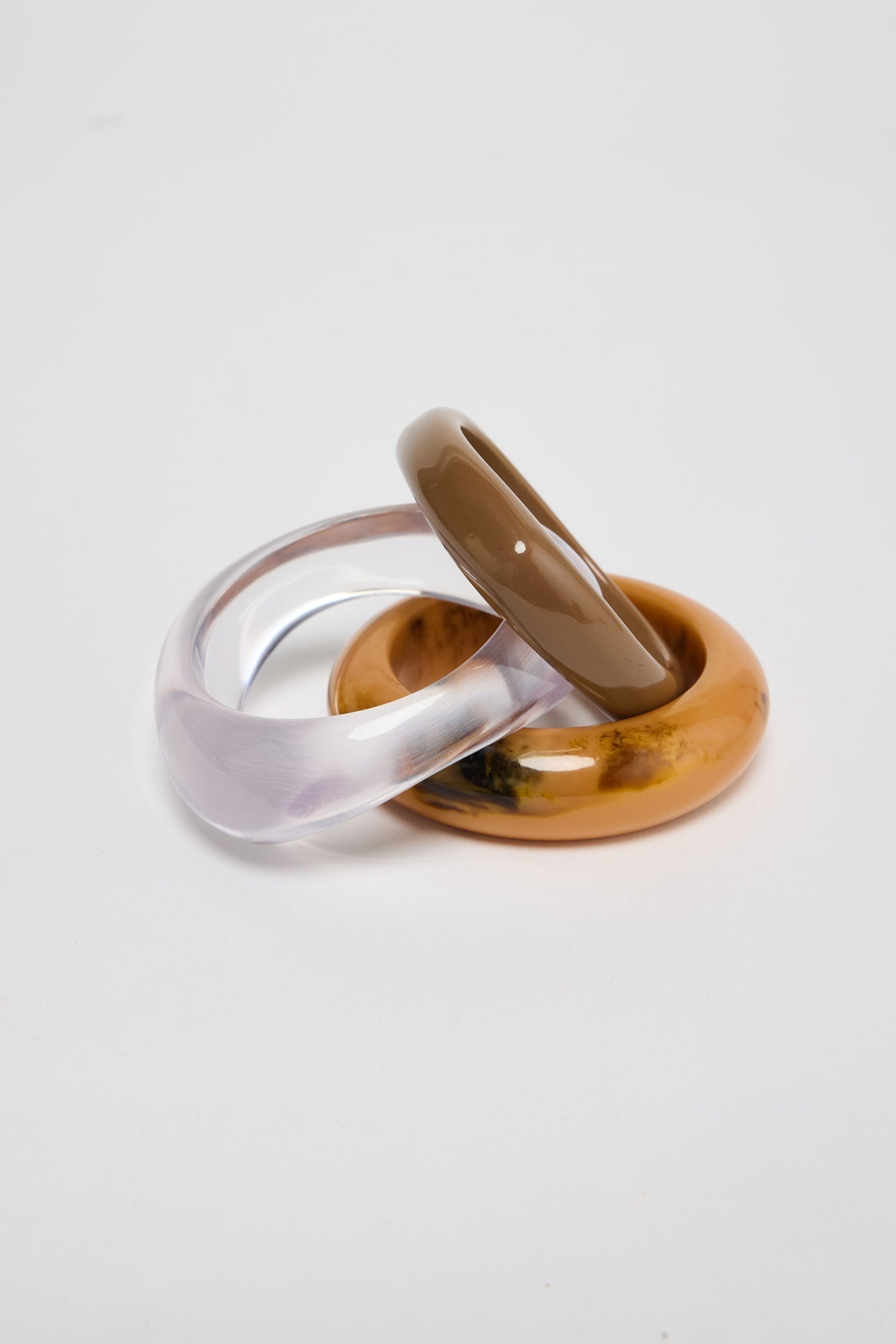 Close-up of three resin bangles showing translucent lilac, taupe and mustard-amber marbled textures