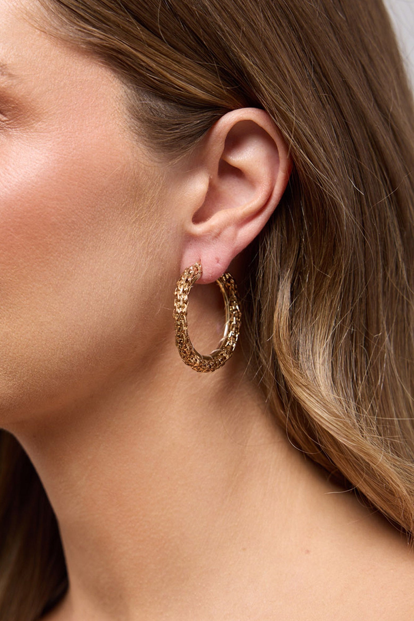 Close-up of the Poppy Earrings in Gold worn on the ear, highlighting the lightweight hoop silhouette