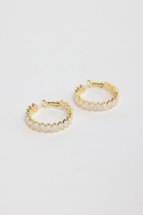 Oasis Earrings in Gold – gold-tone hoop earrings fully set with sparkling baguette crystals, shown flat on a white background.