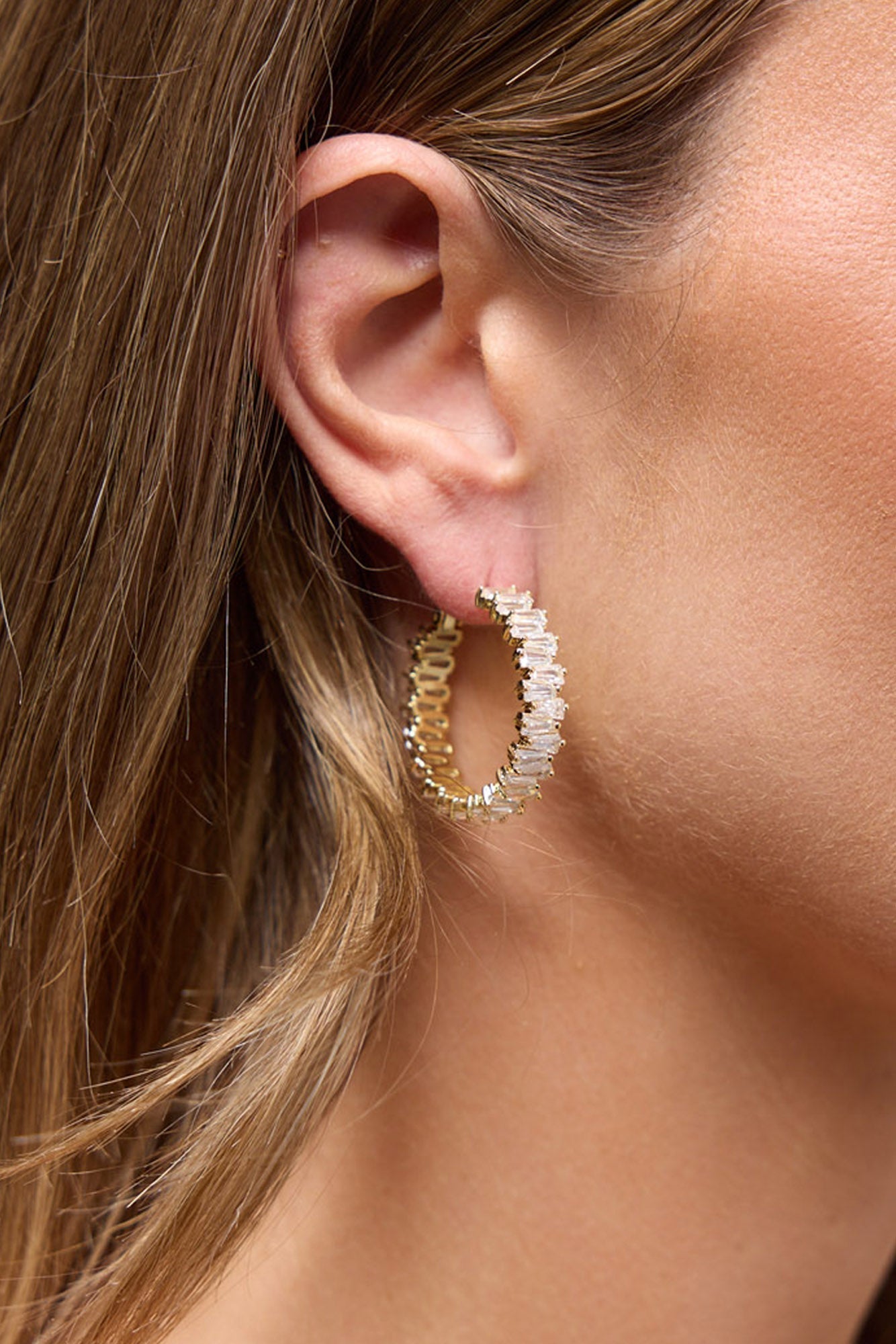 Oasis Earrings in Gold worn on the ear, showing the crystal-lined gold hoop close up against the lobe.
