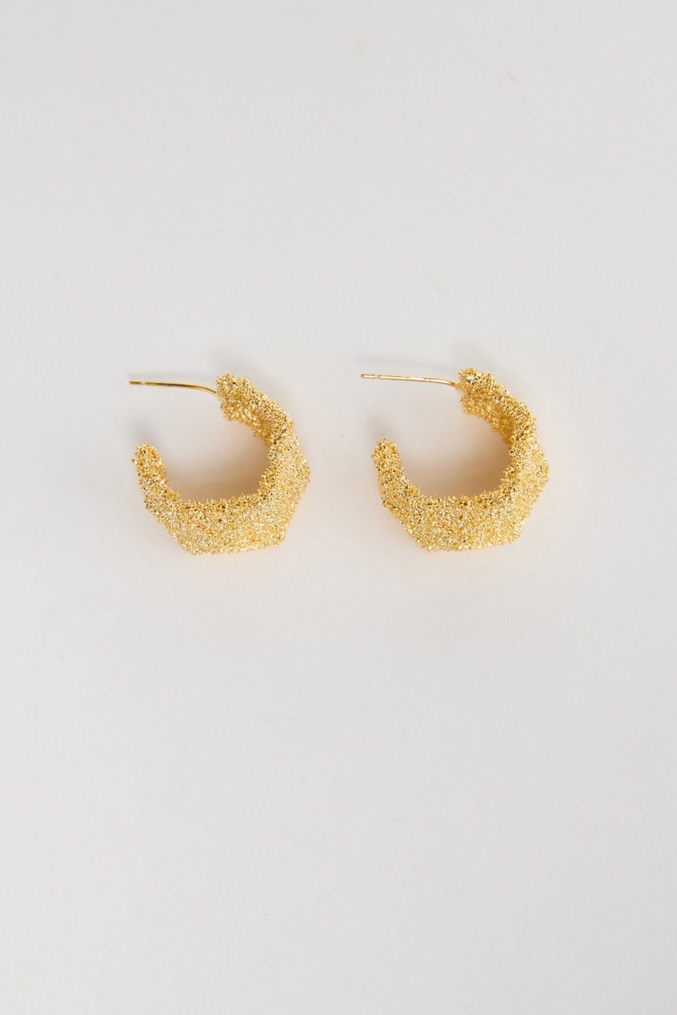 Catalina Earrings in Gold – small textured gold-tone hoop earrings with a granulated, glittering finish, shown flat on a white background.