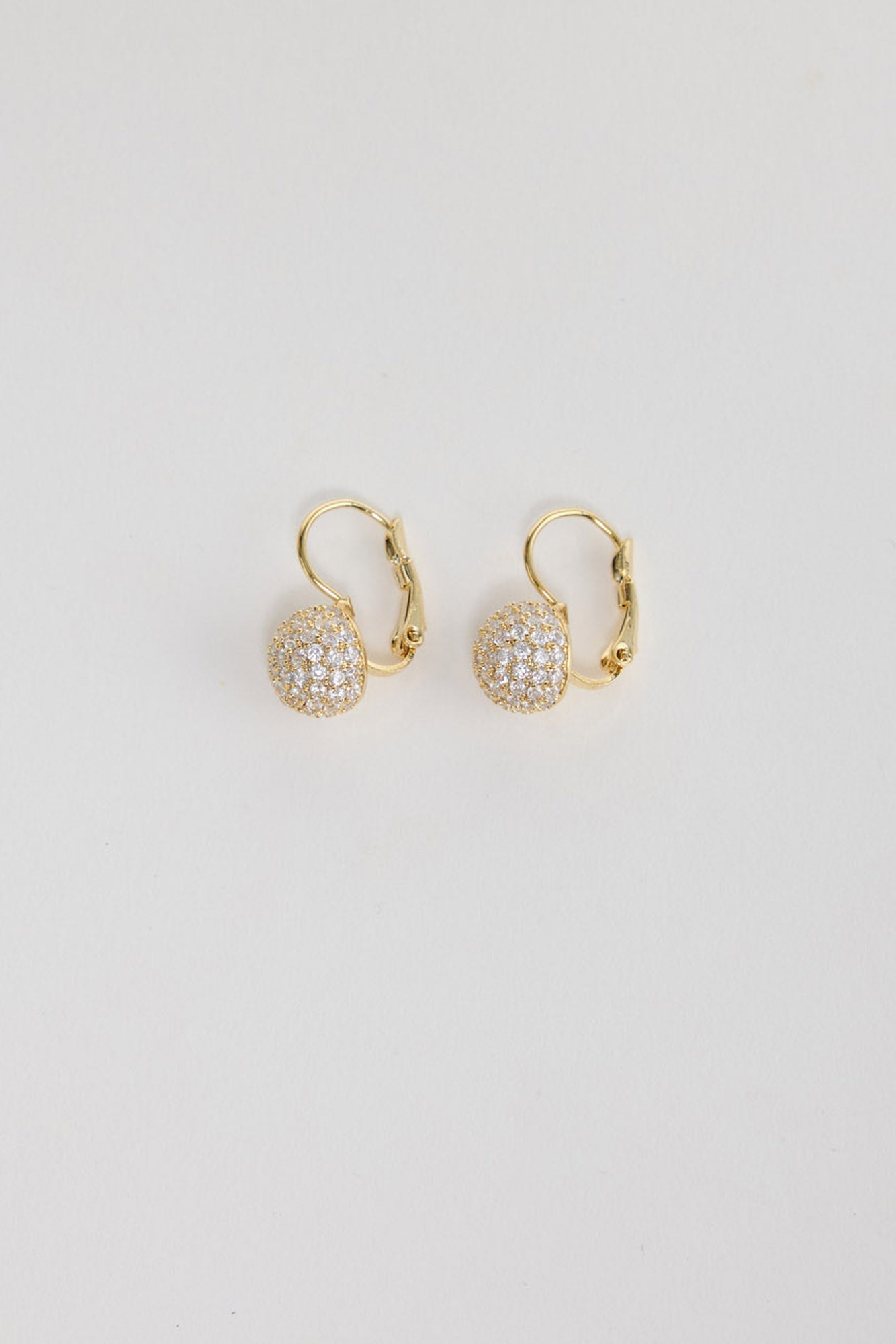 Positano Earrings in Gold – gold-tone leverback earrings with a pave crystal ball charm, shown flat on a white background.