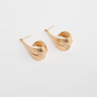 Lagoona Earrings in Gold – sculptural curved gold-tone teardrop earrings shown flat on a white background.