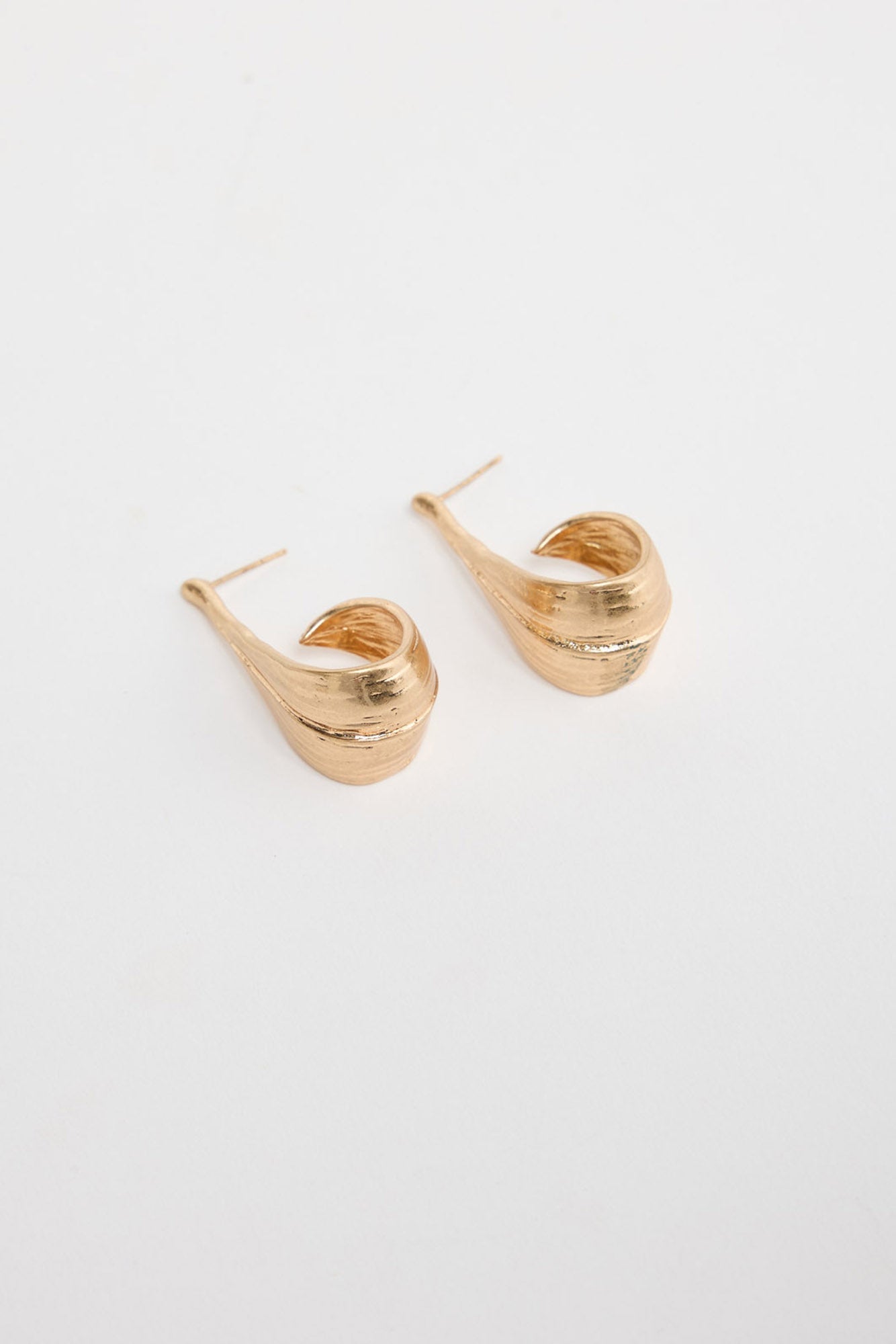 Lagoona Earrings in Gold – sculptural curved gold-tone teardrop earrings shown flat on a white background.