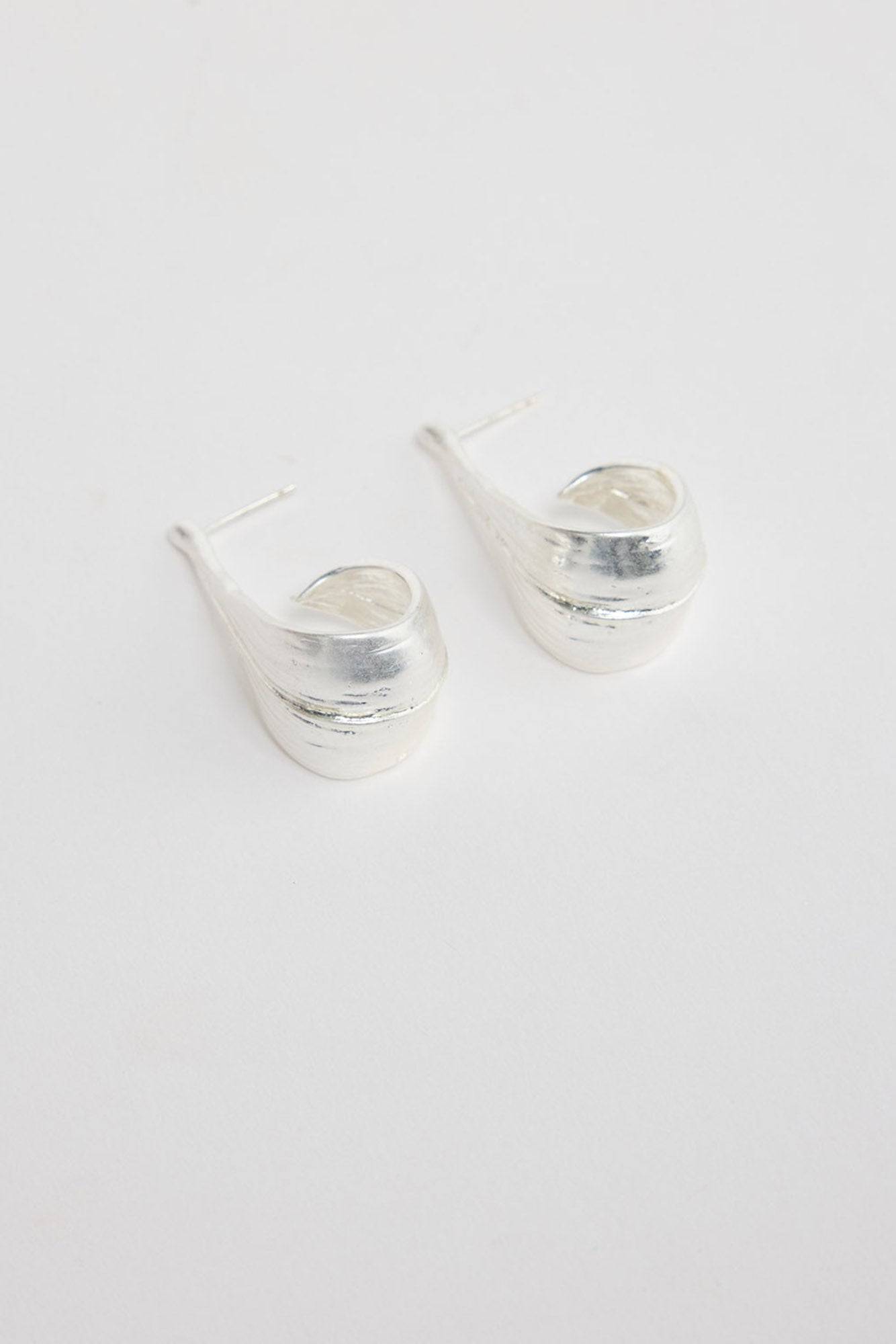 Lagoona Earrings in Silver – sculptural curved silver-tone teardrop earrings shown flat on a white background.