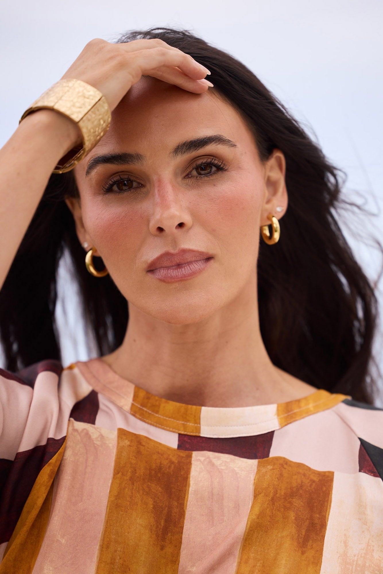 Model wearing Thick Hoops L in Gold paired with a printed top and gold cuff, campaign shot.