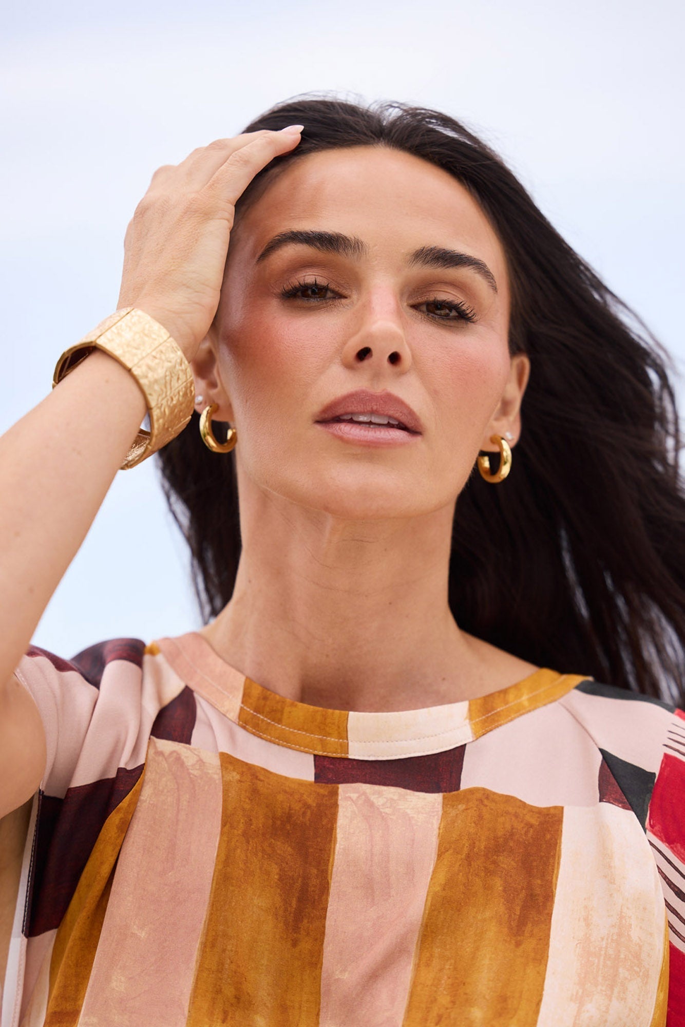 Close-up campaign shot of model wearing Thick Hoops L in Gold with a gold cuff bracelet.