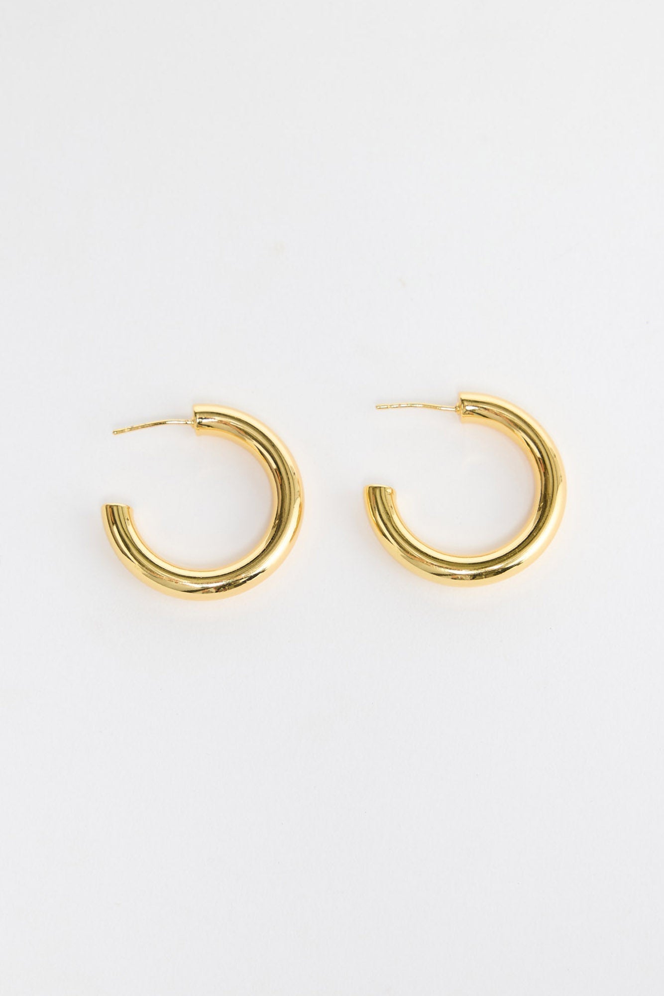 Thick Hoops L in Gold – large polished gold-tone tube hoop earrings shown flat on a white background.