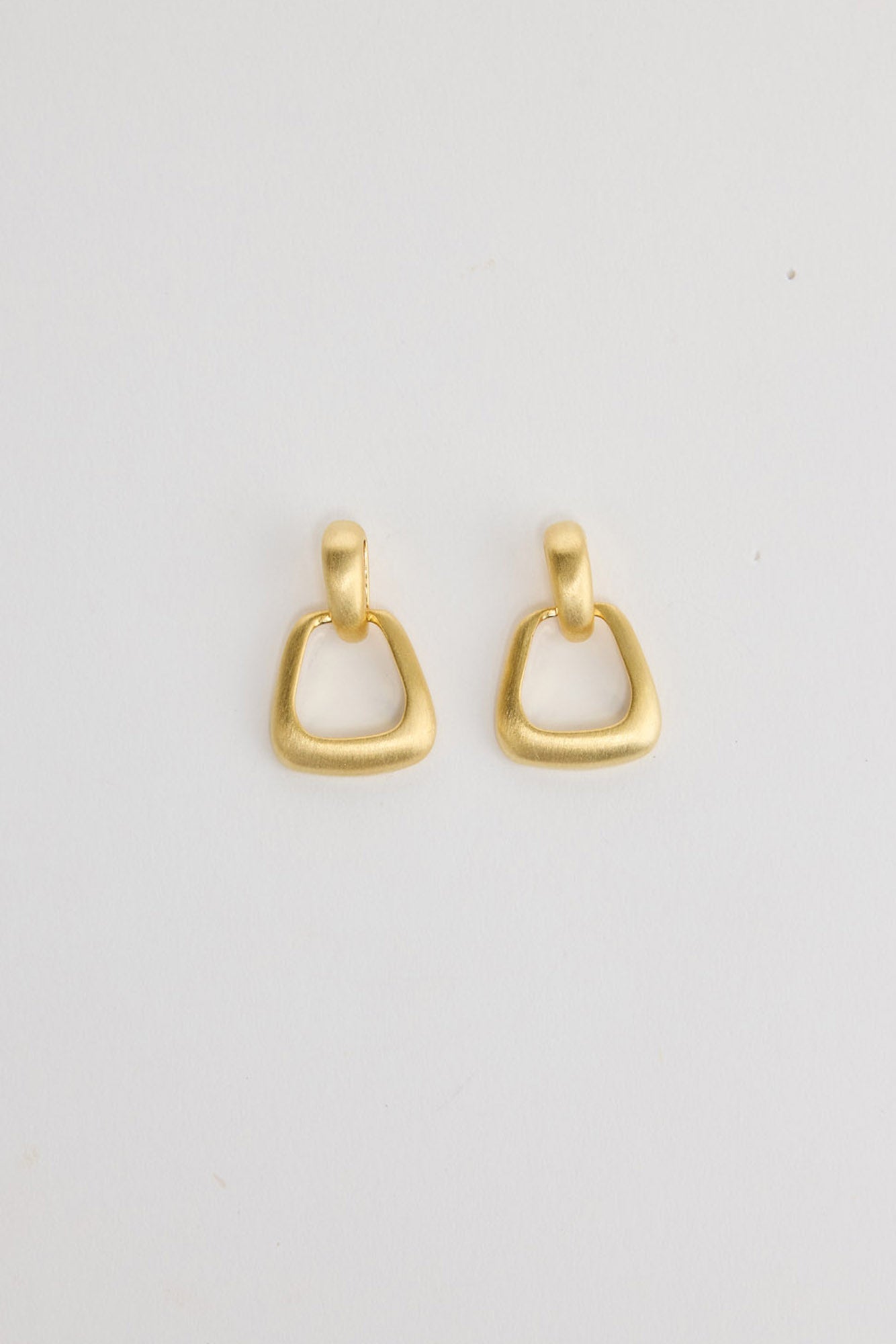 Swell Earrings in Gold – matte gold-tone geometric ring drop earrings shown flat on a white background.
