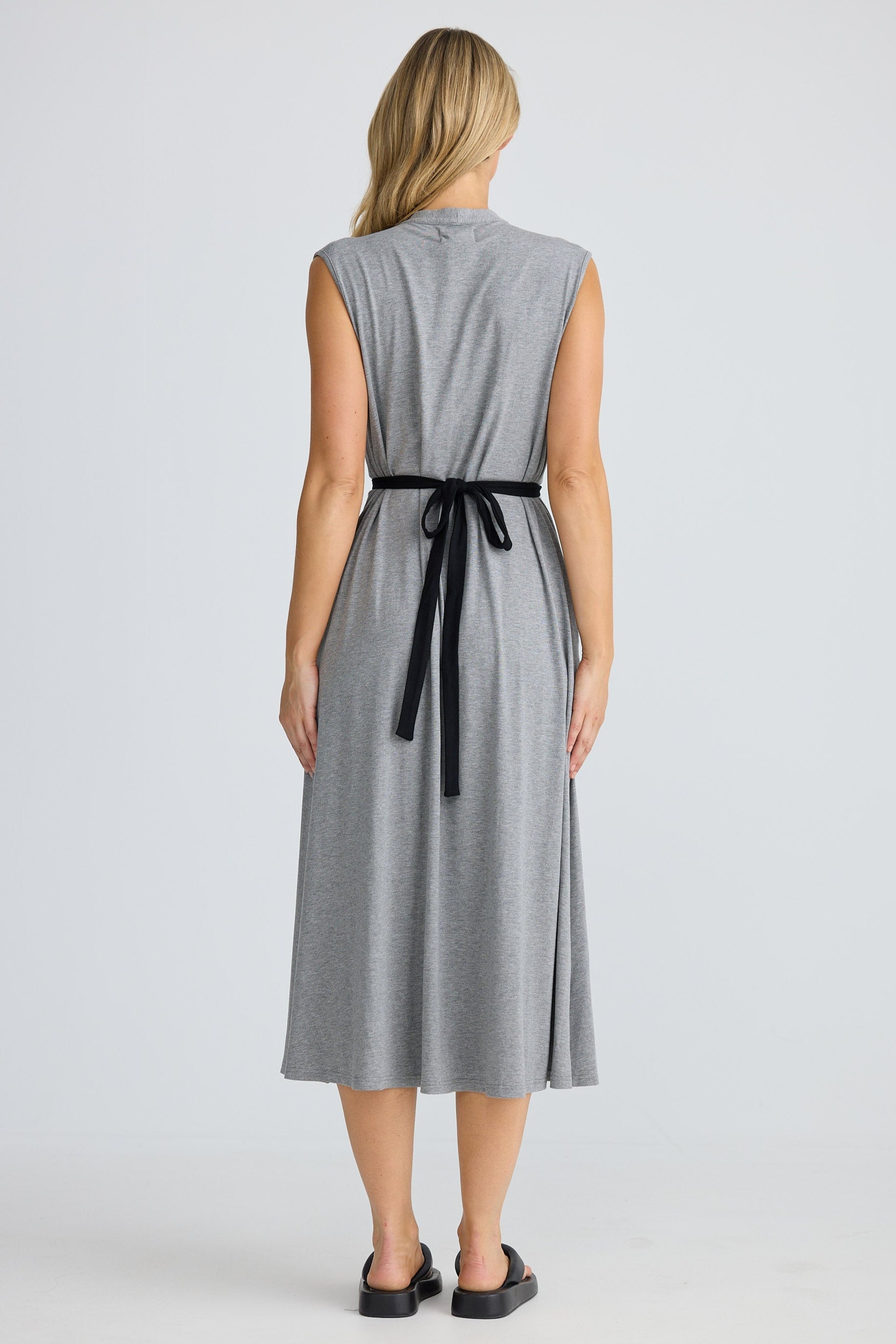 Woman wearing a gray dress with a black belt on a white background
